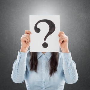 Young woman holding interrogation symbol in front of her face